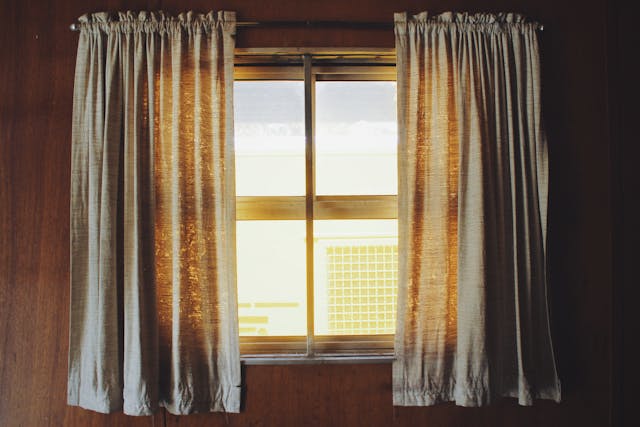 Some curtains hanging over a bright window.