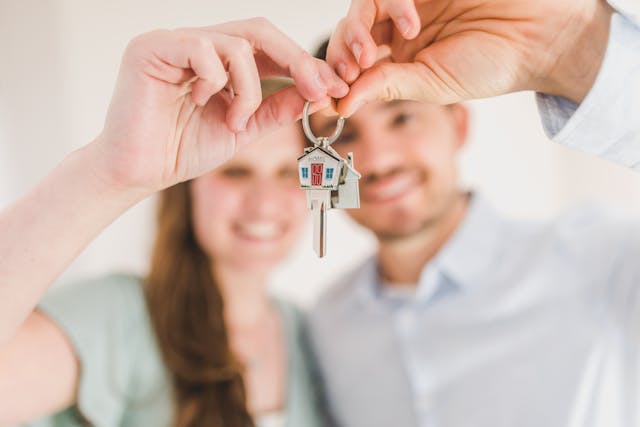 A couple holding up a pair of house keys.